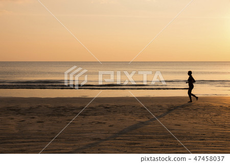Woman running on the beach at sunset. Woman running on the beach at sunset. 47458037