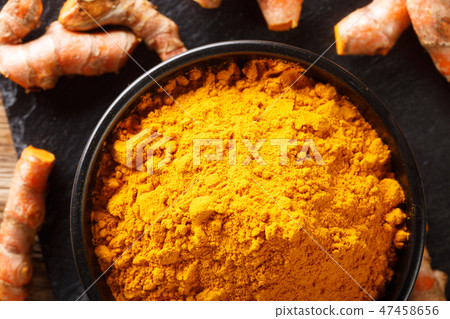 Ground fresh turmeric in a bowl and root close-up 47458656