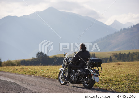 Biker in black leather outfit driving modern powerful motorcycle along sunny road on summer day. Biker in black leather outfit driving modern powerful motorcycle along sunny road on summer day. 47459246
