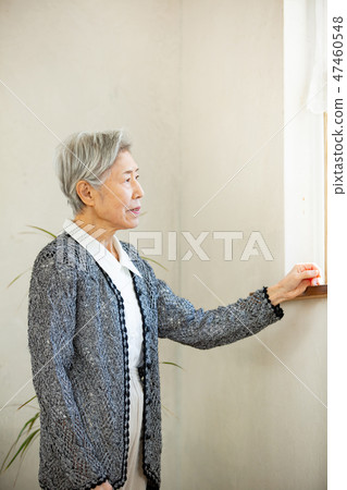 Senior woman standing at the window 47460548