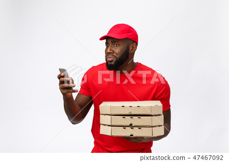 Delivery Concept: Handsome african pizza delivery man talking to mobile with shocking facial Delivery Concept: Handsome african pizza delivery man talking to mobile with shocking facial 47467092
