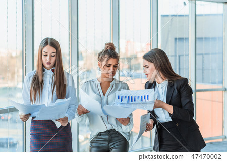 Three business guys in the office. Hold the paper in your hands carefully looking at them Three business guys in the office. Hold the paper in your hands carefully looking at them 47470002