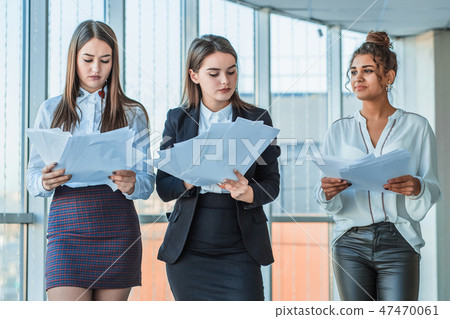 Three young beautiful brunette business ladies in the office. All serious, talking with each other Three young beautiful brunette business ladies in the office. All serious, talking with each other 47470061