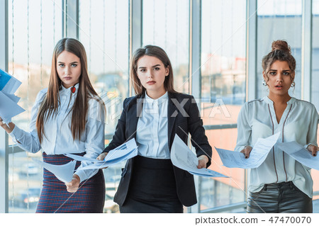 Three young beautiful brunette business ladies in the office. All serious, talking with each other Three young beautiful brunette business ladies in the office. All serious, talking with each other 47470070