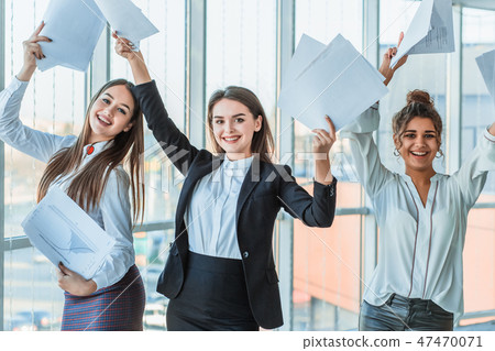 Three young beautiful brunette business ladies in the office. All happy dancing with Three young beautiful brunette business ladies in the office. All happy dancing with 47470071