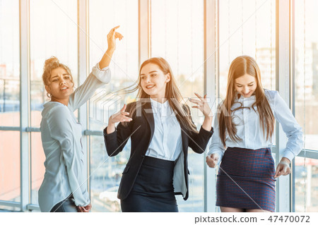 Three young beautiful brunette business ladies in the office. All happy dancing with Three young beautiful brunette business ladies in the office. All happy dancing with 47470072