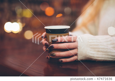 female hands holding a paper cup with hot coffee female hands holding a paper cup with hot coffee 47471636