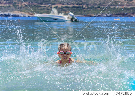 Young girl at yhe sea having fun and splashing water in summer 47472990