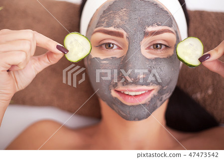 Beautiful woman having clay facial mask apply by beautician. Beautiful woman having clay facial mask apply by beautician. 47473542