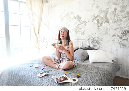 Young craing woman eating sweets in bedroom Young craing woman eating sweets in bedroom 47473629