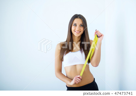 Diet. The girl taking measurements of her body, white background. 47473741