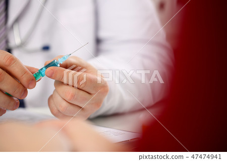 Physician injector arms in sterile uniform holding syringe Physician injector arms in sterile uniform holding syringe 47474941