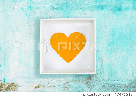 Yellow paper heart in white cardboard box on old turquoise metal background 47475515