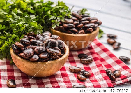 Uncooked beans in wooden bowles on kitchen table. 47476357