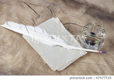 Quill pen and glass inkwell with old letters Quill pen and glass inkwell with old letters 47477510