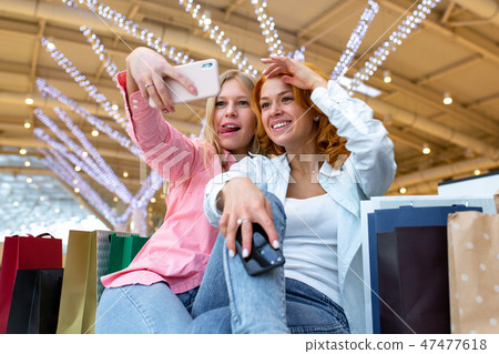 Two happy friends is taking selfie while shopping in mall. Two happy friends is taking selfie while shopping in mall. 47477618