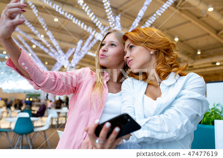 Two happy friends is taking selfie while shopping in mall. Two happy friends is taking selfie while shopping in mall. 47477619