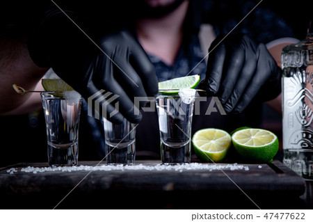 Bartender in decorates tequila lime shots. Mexican, alcohol in shot glasses Bartender in decorates tequila lime shots. Mexican, alcohol in shot glasses 47477622