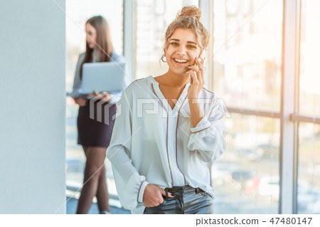 Business lady at the office talking to a smartphone. Happy smiling Caucasian business woman busy Business lady at the office talking to a smartphone. Happy smiling Caucasian business woman busy 47480147