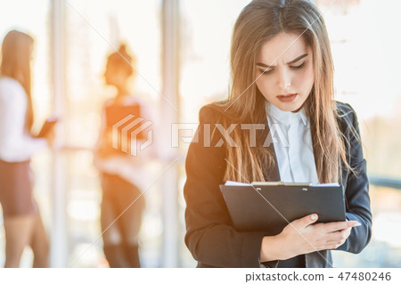 Beautiful brunette business woman in white suit with folder of documents in her hands outdoors. copy Beautiful brunette business woman in white suit with folder of documents in her hands outdoors. copy 47480246