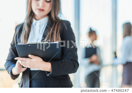 Beautiful brunette business woman in white suit with folder of documents in her hands outdoors. copy Beautiful brunette business woman in white suit with folder of documents in her hands outdoors. copy 47480247