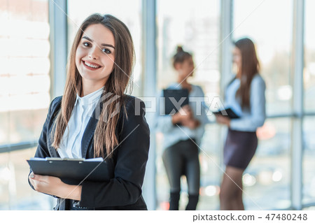 Beautiful brunette business woman in white suit with folder of documents in her hands outdoors. copy Beautiful brunette business woman in white suit with folder of documents in her hands outdoors. copy 47480248