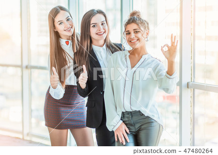 Young pretty business girls show a good gesture. Dressed in classic clothes Young pretty business girls show a good gesture. Dressed in classic clothes 47480264