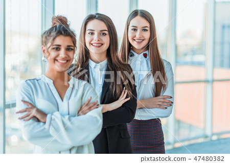 With pleasure, three business women cross their arms, looking at the camera. Dressed in white With pleasure, three business women cross their arms, looking at the camera. Dressed in white 47480382