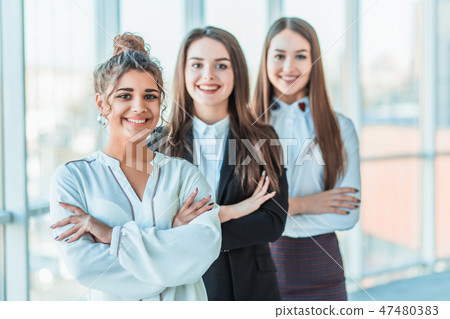 With pleasure, three business women cross their arms, looking at the camera. Dressed in white With pleasure, three business women cross their arms, looking at the camera. Dressed in white 47480383