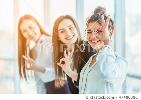 Young pretty business girls show a good gesture. Dressed in classic clothes, smiling copy space Young pretty business girls show a good gesture. Dressed in classic clothes, smiling copy space 47480386