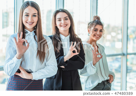 Young pretty business girls show a good gesture. Dressed in classic clothes, smiling copy space Young pretty business girls show a good gesture. Dressed in classic clothes, smiling copy space 47480389