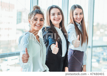 Three young business girls in the office. Dressed in classic clothing style Three young business girls in the office. Dressed in classic clothing style 47480401