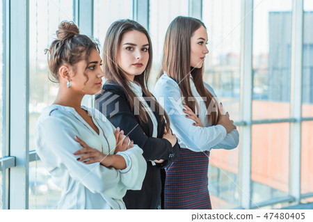 With pleasure, three business women cross their arms, looking at the camera. With pleasure, three business women cross their arms, looking at the camera. 47480405