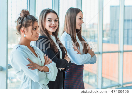 With pleasure, three business women cross their arms, looking at the camera. With pleasure, three business women cross their arms, looking at the camera. 47480406
