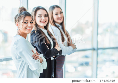 With pleasure, three business women cross their arms, looking at the camera. With pleasure, three business women cross their arms, looking at the camera. 47480856
