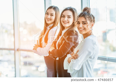 With pleasure, three business women cross their arms, looking at the camera. With pleasure, three business women cross their arms, looking at the camera. 47480857