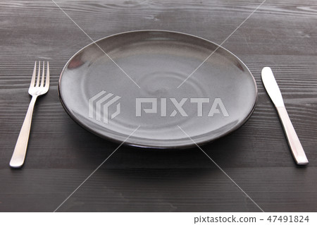 Black dish and cutlery placed on a black table Black dish and cutlery placed on a black table 47491824