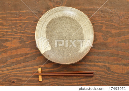 A dish made of earth and chopsticks placed on a brown table 47493951