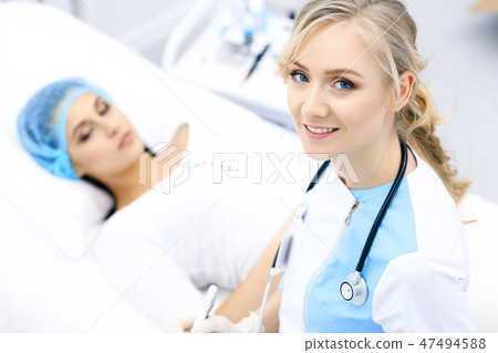 Female doctor and young woman patient in hospital. Physicians examine girl lying at the bed, view Female doctor and young woman patient in hospital. Physicians examine girl lying at the bed, view 47494588