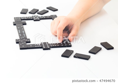 Kids hand is holding a domino tile with Kids hand is holding a domino tile with 47494670
