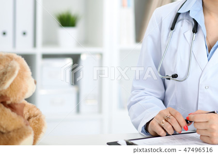 Unknown female doctor working at the desk with clipboard in hospital and filling up medical history Unknown female doctor working at the desk with clipboard in hospital and filling up medical history 47496516