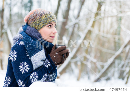 Woman freezing on a cold winter day warming herself up with hot drink 47497454