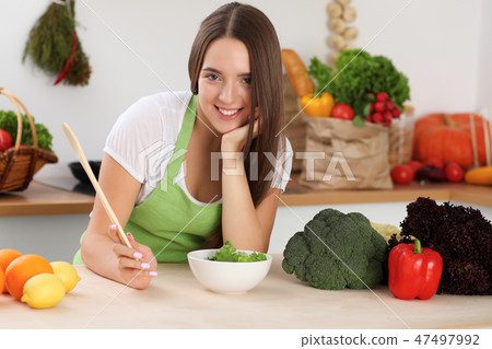 Young woman cooking in kitchen. Householding, tasty food and digital technology in lifestyle Young woman cooking in kitchen. Householding, tasty food and digital technology in lifestyle 47497992