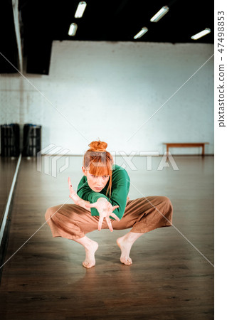 Cute red-haired yoga teacher in a green turtleneck looking focused 47498853