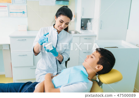 Female dentist shows dentures to little boy Female dentist shows dentures to little boy 47500089