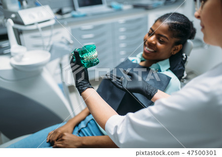 Dentist shows dentures to patient in dental clinic Dentist shows dentures to patient in dental clinic 47500301