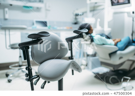Patient on chair in dental clinic, back view Patient on chair in dental clinic, back view 47500304