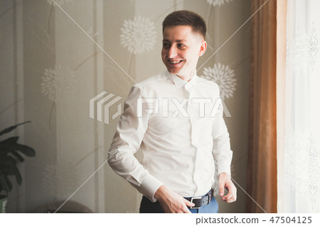 Young handsome man relaxing at his apartment in a hotel after business meeting Young handsome man relaxing at his apartment in a hotel after business meeting 47504125
