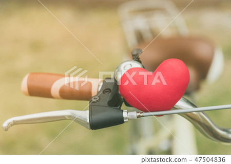 A little red heart pillow on the handlebar. 47504836