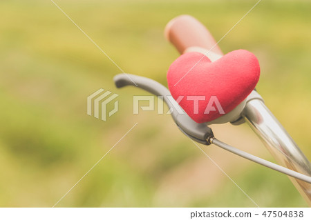 A little red heart pillow on the handlebar. 47504838